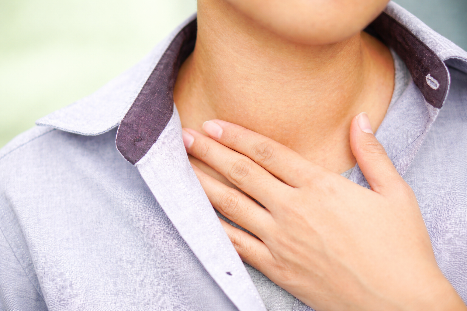 Person touching their goiter thyroid neck with a blurred background